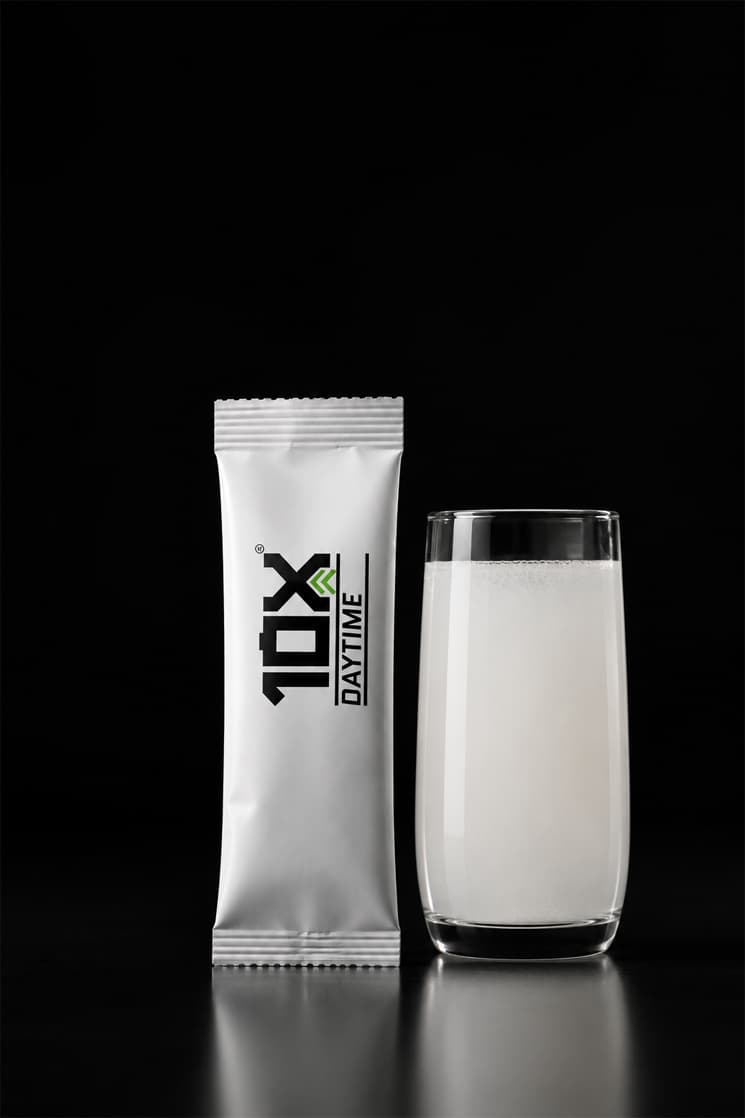 A 10X Daytime sachet beside a tall glass of the prepared drink